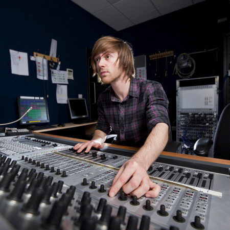 Human at mixing board with fingers on dial