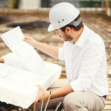 Human wearing white hardhat and looking at paper